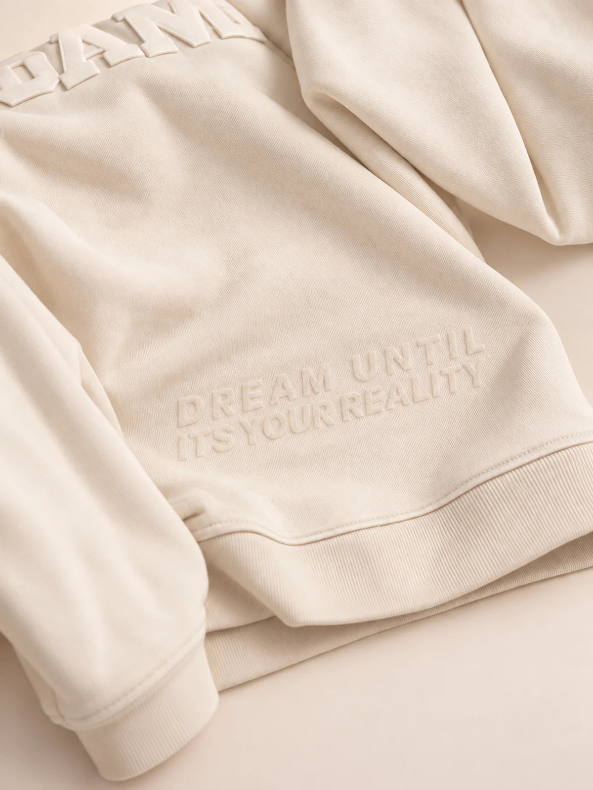 Cream DREAM hoodie: DREAM UNTIL ITSYOURREALITY embossed into the fleece